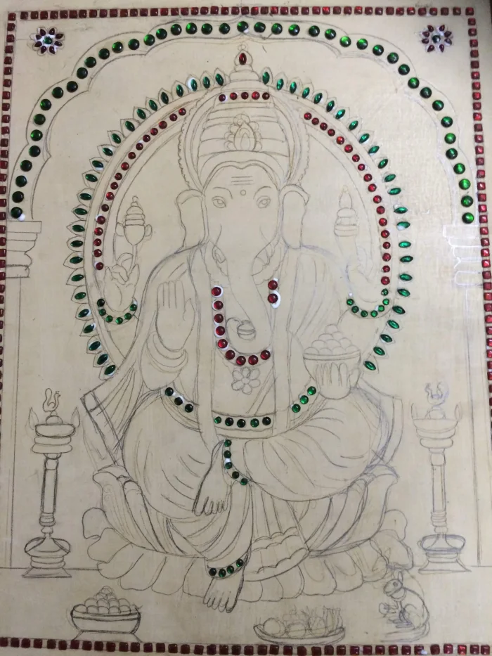 Ganapati drawing on a prepared board with stones being set along the outlines